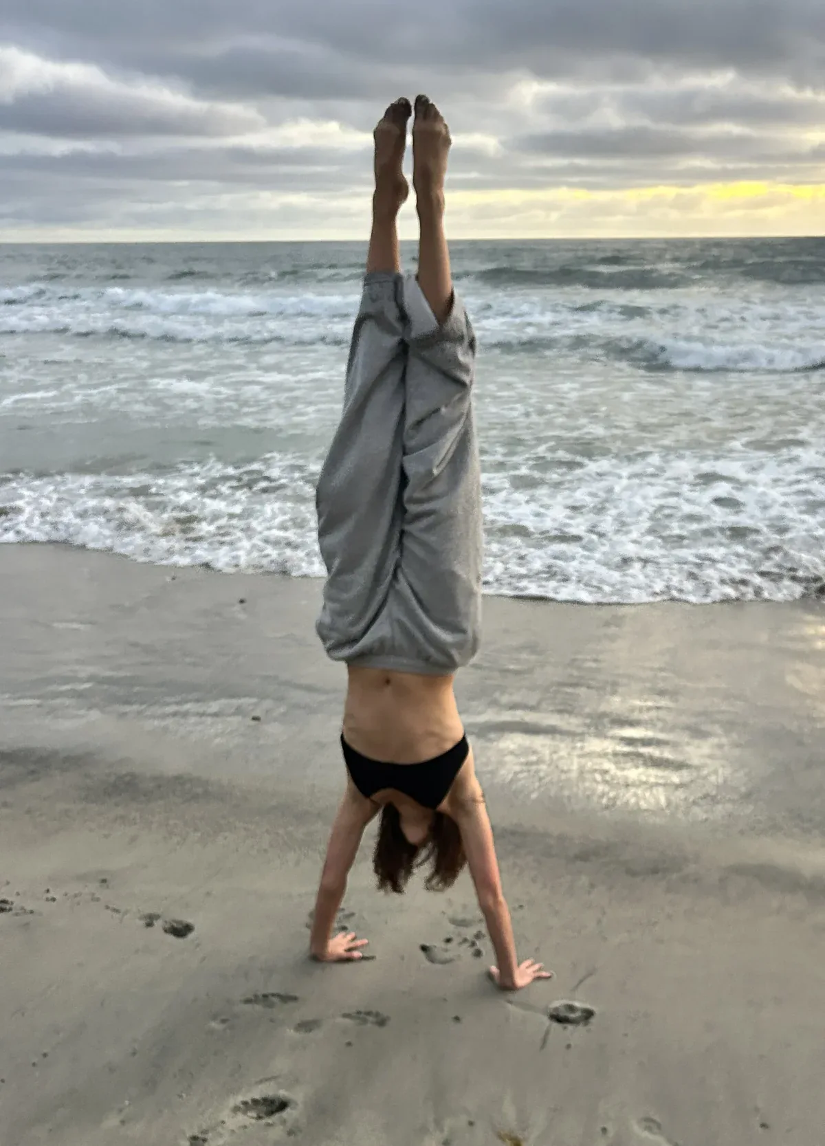 Hannah doing a handstand on the beach at sunset